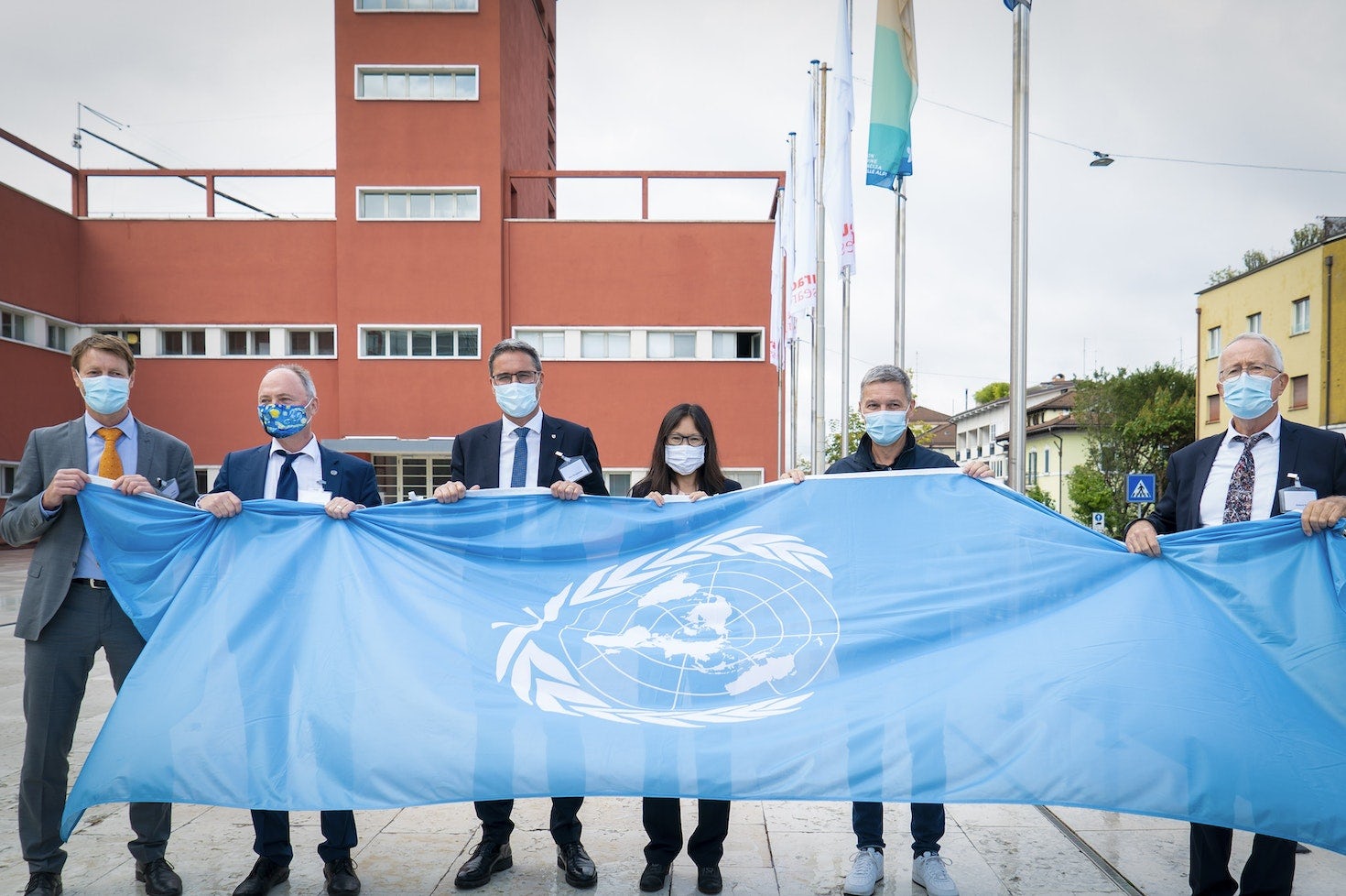 this picture shows the UN flag raising that took place on September 25th, 2020. The event marked the official establishment of the United Nations duty station in Bolzano, where the center Global Mountain Safeguard Research (GLOMOS) is jointly run by UNU-EHS and Eurac Research. Present to the event were (from left to right): GLOMOS directors Stefan Schneiderbauer and Joerg Szarzynski, South Tyrol governor Arno Kompatscher, UNU Vice-Rector for Europe and UNU-EHS’ Director Shen Xiaomeng, Eurac Research President Roland Psenner and Director Stephan Ortner.